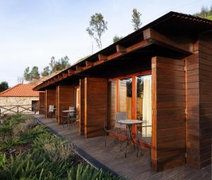 a wooden house with a deck with tables and chairs at Casa do Avô in Cinfães