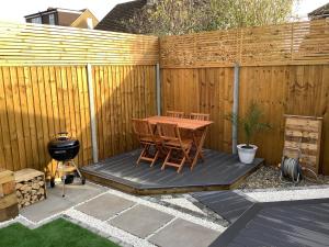 a patio with a wooden fence with a table and a grill at Carolyn’s Place in Ruislip