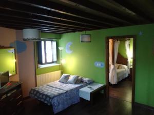 1 dormitorio con paredes verdes, 1 cama y espejo en Luna de Vilar en Vilarpescozo
