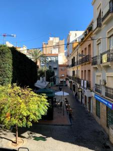une rue de la ville avec des tables, des chaises et des bâtiments dans l'établissement Encantador loft en centro tradicional, à Alicante