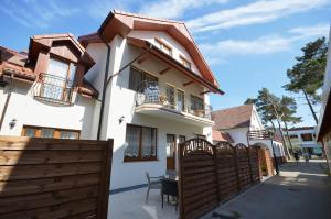 a white house with a wooden fence in front of it at Pokoje Sztormowa 15 in Pogorzelica +17 photos