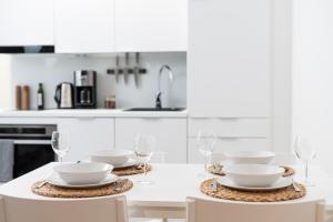 uma cozinha branca com uma mesa com pratos e copos de vinho em ULEABO New 37m2 Studio em Oulu