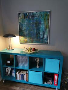 a blue book shelf with books and a lamp at Gruga Apartment an der Messe in Essen