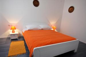 a bedroom with a bed with an orange blanket and two lamps at Apartment Fiorenini 2 in Mlini