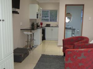 ein Wohnzimmer mit einem roten Stuhl und eine Küche in der Unterkunft a Dam's View Accommodation in Queenstown