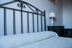 a bedroom with a bed with a white blanket and a lamp at Apartamentos Corona in Comillas