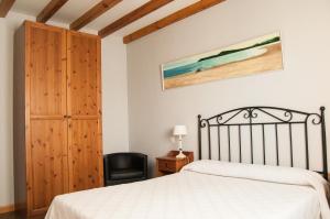 a bedroom with a bed and a black chair at Apartamentos Corona in Comillas