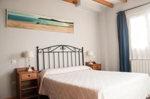a bedroom with a white bed and a painting on the wall at Apartamentos Corona in Comillas