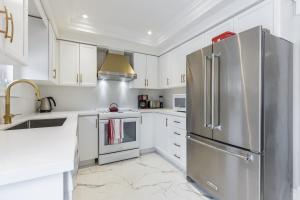 a kitchen with white cabinets and a stainless steel refrigerator at Luxury Adventure, Rutherford Go station & Wonderland in Vaughan