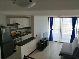 a kitchen with blue curtains and a tv in a room at departamento NEO vista al mar 2 piezas in Iquique