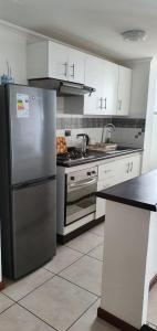 a kitchen with a stainless steel refrigerator and white cabinets at departamento NEO vista al mar 2 piezas in Iquique