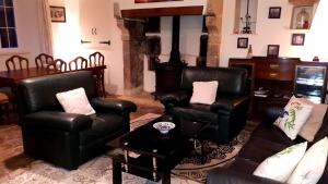 a living room with black leather chairs and a table at L' Anpeg Maison de vacances in Besneville
