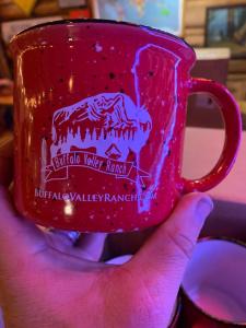 a hand holding a red cup with a horse on it at Heart Six Ranch in Moran