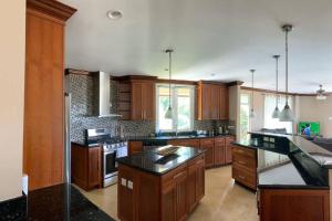 a large kitchen with wooden cabinets and black counter tops at Villa Xona in Castries