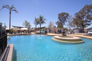 a large swimming pool in a tropical setting at Ingenia Holidays Hunter Valley in Cessnock
