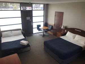 une chambre d'hôtel avec un lit, une table et des chaises dans l'établissement Highlander Hotel Bar Kitchen Rooftop, à Adélaïde