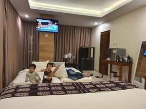 two children sitting on a bed in a hotel room at Kalton Hotel in Labuan Bajo