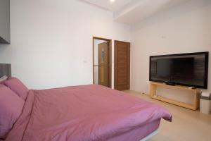 um quarto com uma cama e uma televisão de ecrã plano em Travelers Hostel em Magong