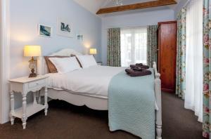 a bedroom with a large white bed and a window at Kuranui Cottage in Thames