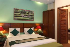 a bedroom with a bed and two lamps at The Green Zhurga Suite in Kerobokan