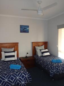 a bedroom with two beds with blue and white pillows at Gilligan's Kangaroo Island in Baudin Beach