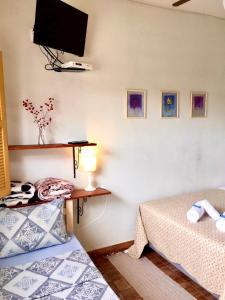 a bedroom with two beds and a tv on the wall at Pousada Vovô Juca Tiradentes in Tiradentes