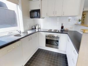 a white kitchen with a sink and a oven at Courtyard Loft 12 The Stables Perisher in Perisher Valley