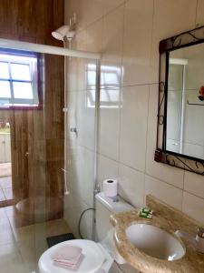ein Bad mit einer Dusche, einem Waschbecken und einem Spiegel in der Unterkunft Pousada Vovô Juca Tiradentes in Tiradentes