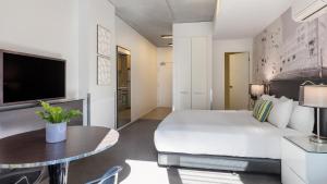 a bedroom with a bed and a table and a tv at Oaks Melbourne on William Suites in Melbourne +37 photos
