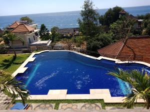 a large blue swimming pool next to a house at Bamboo Bali in Amed