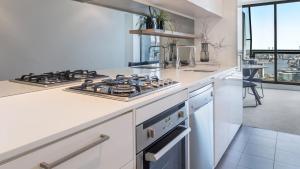 a kitchen with a stove top oven and a sink at Oaks Melbourne on William Suites in Melbourne
