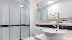 a bathroom with a shower, sink, and mirror at Oaks Melbourne on William Suites in Melbourne