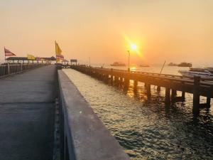 a pier with the sun setting over the water at The Best Hostel Koh Payam in Ko Phayam