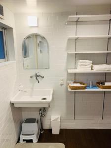 ein weißes Badezimmer mit Waschbecken und Spiegel in der Unterkunft 宿＆喫茶 アガリメージョー in Uruma