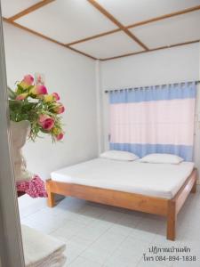 1 dormitorio con 1 cama y un jarrón de flores en ปฎิภาณบ้านพัก en Mae Hong Son