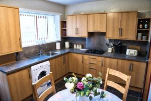 una cocina con una mesa con un jarrón de flores en North Coast Property - North Coast House en Thurso