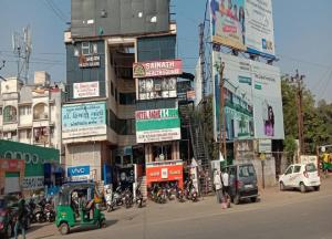 a busy city street with cars and motorcycles in front of a building at Radhe-The Hotel in Vadodara