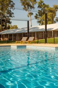 a swimming pool with two benches in front of a building at Serafino McLaren Vale in McLaren Vale