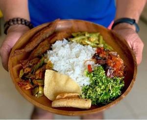 Kumari Guest House في بولوناروا: شخص يحمل وعاء من الطعام مع الأرز والخضروات