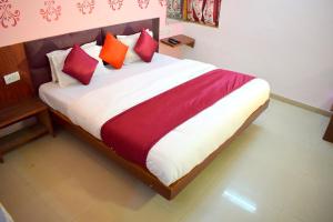 a bedroom with a bed with red and orange pillows at Radhe-The Hotel in Vadodara