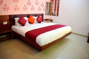 a bedroom with a bed with red and white pillows at Radhe-The Hotel in Vadodara