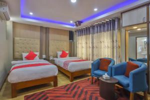 a hotel room with two beds and two chairs at Hotel Marinha in Pashupatināth