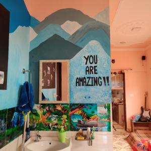 a bathroom with a sink with a painting on the wall at Tebaar Backpackers in Rishīkesh