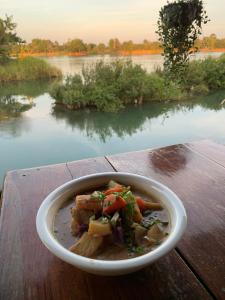a bowl of food on a table near a river at CrazyGecko in Don Det