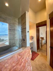 a bathroom with a tub and a shower with a window at The Grand Hacienda Estate with Breakfast in Abiquiu