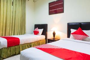 2 camas en una habitación con almohadas rojas y blancas en Super OYO 1682 Greenia Hotel en Kupang