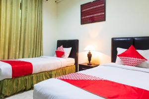 2 camas en una habitación con almohadas rojas y blancas en Super OYO 1682 Greenia Hotel, en Kupang