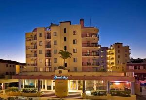 a large building with a palm tree in front of it at Asiatic Suite at Nautilus Mooloolaba in Mooloolaba