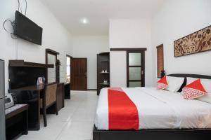 a bedroom with a bed and a desk and a television at OYO 2417 Panen House in Seminyak