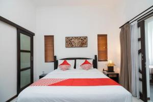 a bedroom with a large bed with red pillows at OYO 2417 Panen House in Seminyak